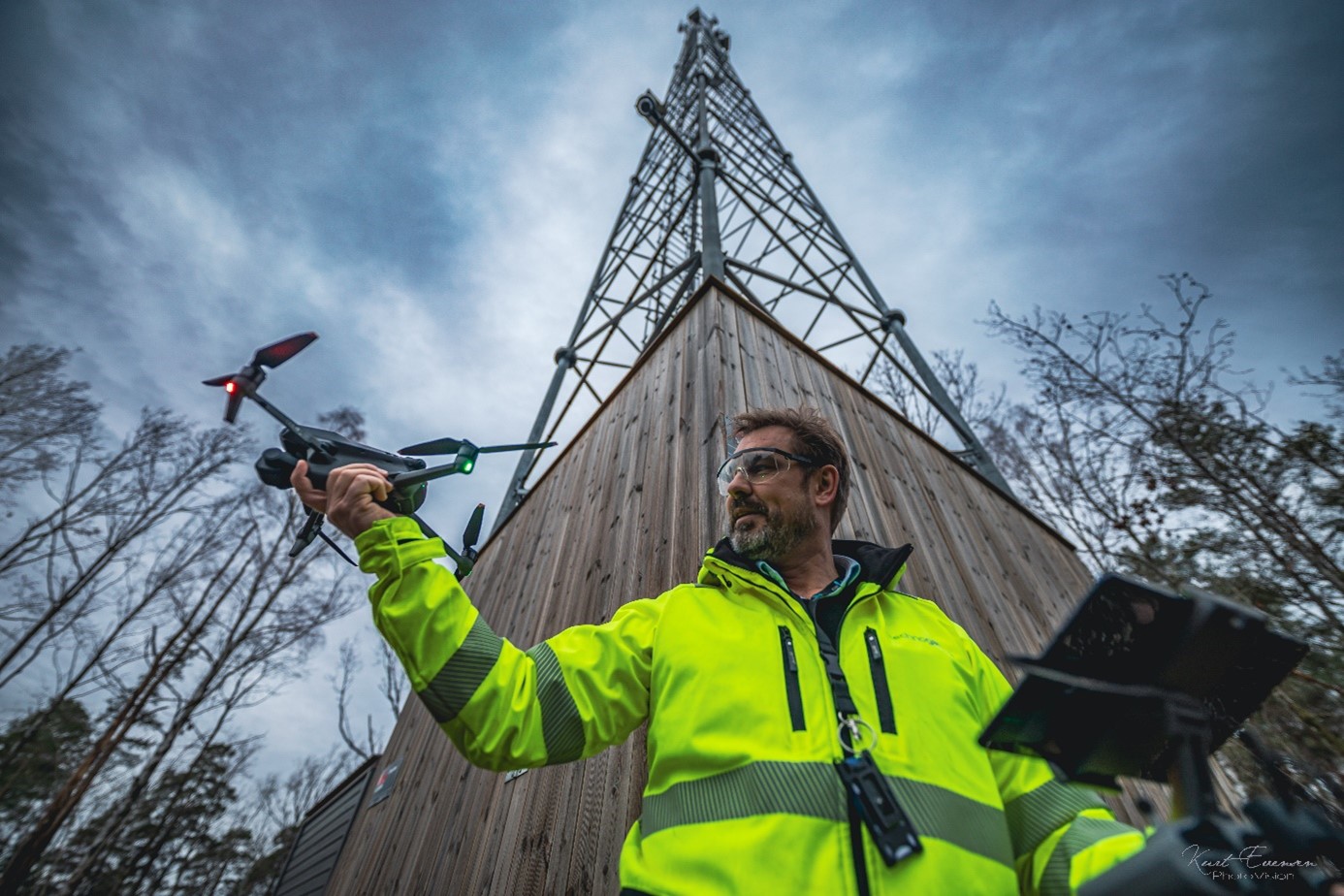 Mann som flyr drone foran antennemast